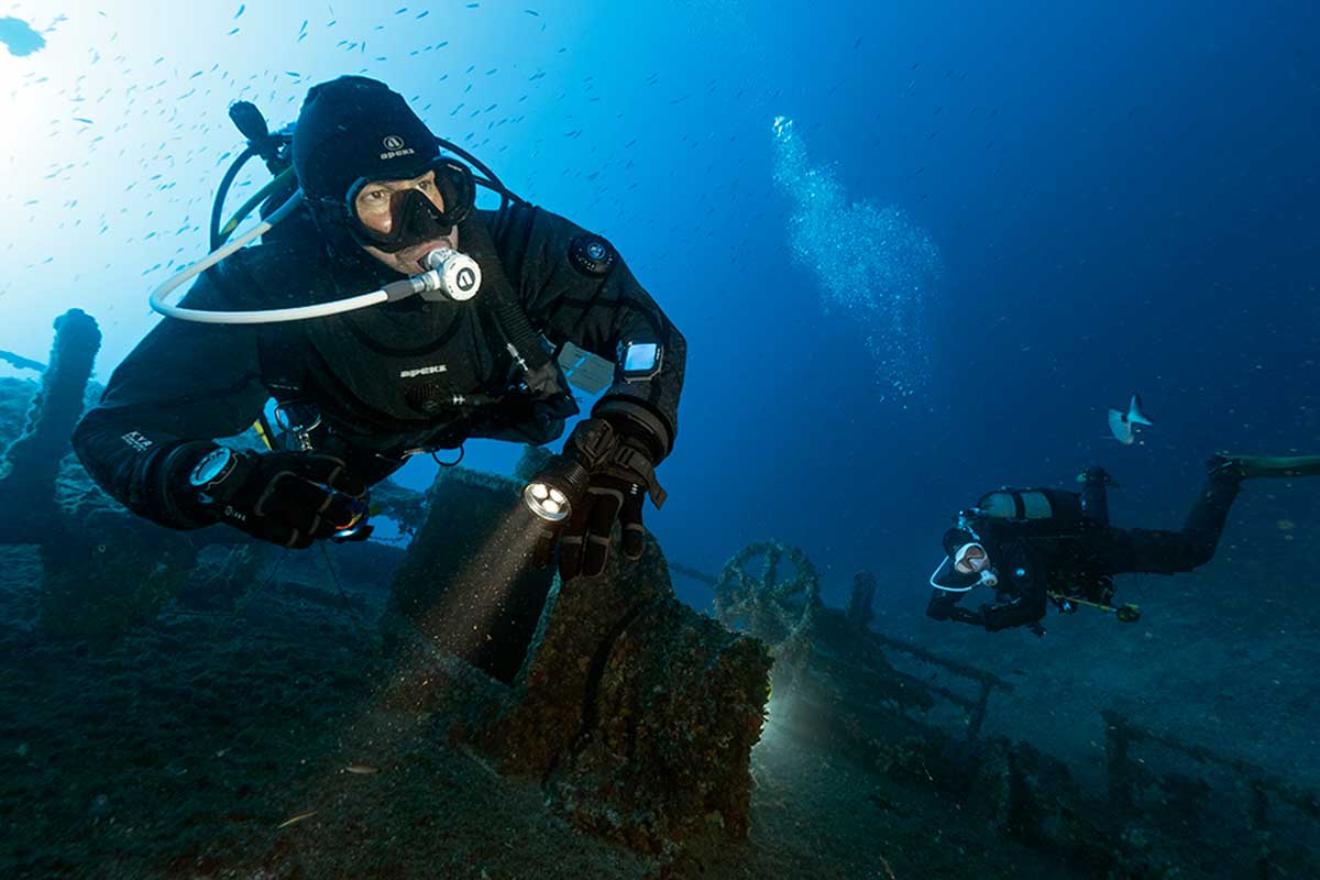 buceador realizando un buceo profundo con traje seco y linterna